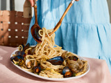 woman tossing pasta with clams