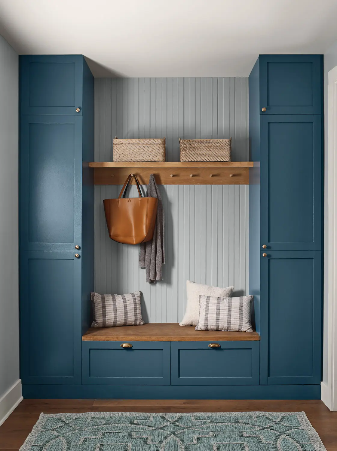 mud room with blue cabinets and a purse hanging on a hook