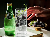 Hand reaching for glass with Perrier bottle