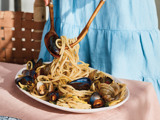 women tossing pasta and clams in shells